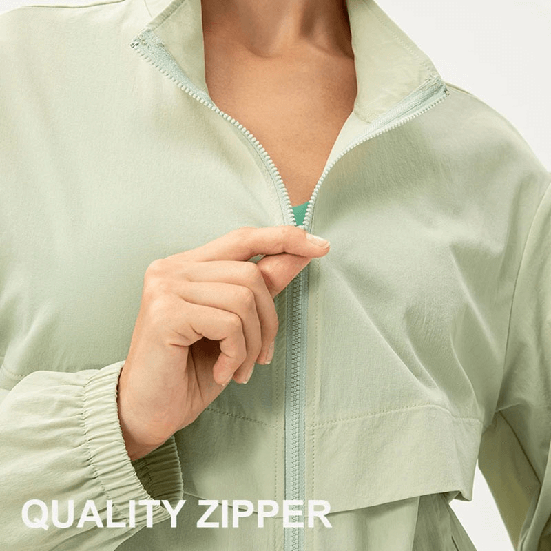 Woman wearing a light green UV protection running windbreaker with quality zipper closure and turn-down collar.